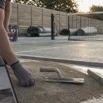 Terres de sport : technicien près d’un terrain de tennis rénové, béton poreux et drainage visible